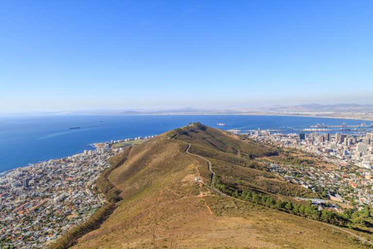 The view looking onto a mountain with the city on either side and the sea further out