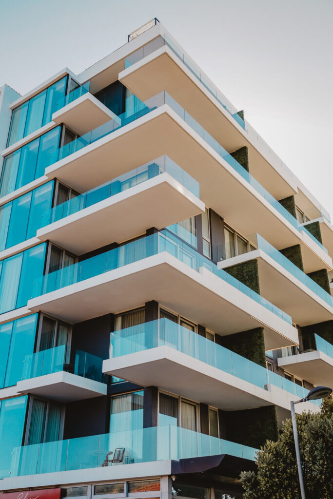 6 floors of a modern apartment building with glass windows and glass balconies extending out towards the right