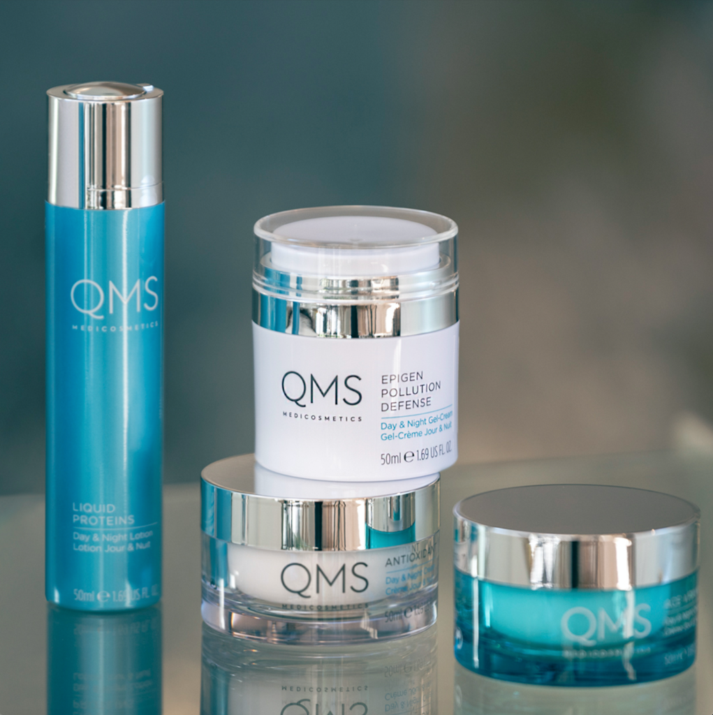 Blue and white bottles of QMS cosmetics displayed on a glass counter